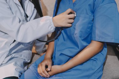 Bir doktor hastasının kalp atışlarını kontrol etmek için steteskop kullanır. Hastaların her yıl sağlık kontrolünden ya da kardiyologdan sağlık kontrolünden geçmeleri gerekir..