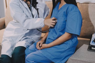 Bir doktor hastasının kalp atışlarını kontrol etmek için steteskop kullanır. Hastaların her yıl sağlık kontrolünden ya da kardiyologdan sağlık kontrolünden geçmeleri gerekir..