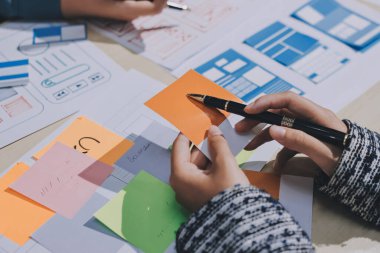 Çalışan bir toplantı sırasında uxui mobil uygulama şablonlarını analiz eden bir grup genç uygulama geliştirici