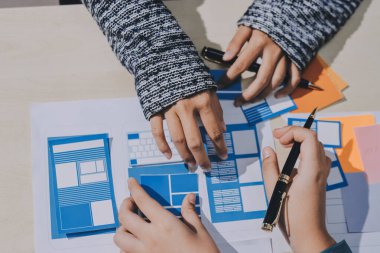 Çalışan bir toplantı sırasında uxui mobil uygulama şablonlarını analiz eden bir grup genç uygulama geliştirici