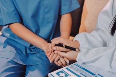 Doktor, klinikteki masada otururken hasta kadına güven veriyor, sadece eller. İlaç ve en iyi hizmet