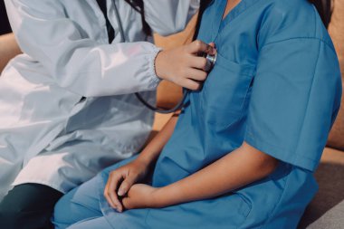 Bir doktor hastasının kalp atışlarını kontrol etmek için steteskop kullanır. Hastaların her yıl sağlık kontrolünden ya da kardiyologdan sağlık kontrolünden geçmeleri gerekir..