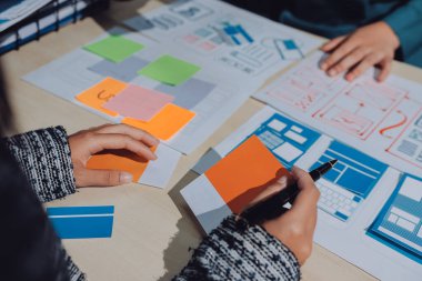 Çalışan bir toplantı sırasında uxui mobil uygulama şablonlarını analiz eden bir grup genç uygulama geliştirici