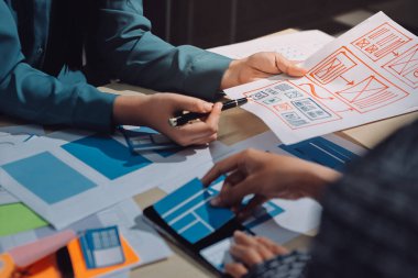 Çalışan bir toplantı sırasında uxui mobil uygulama şablonlarını analiz eden bir grup genç uygulama geliştirici