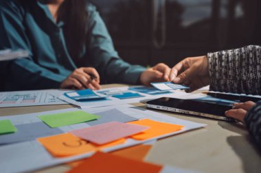 Çalışan bir toplantı sırasında uxui mobil uygulama şablonlarını analiz eden bir grup genç uygulama geliştirici