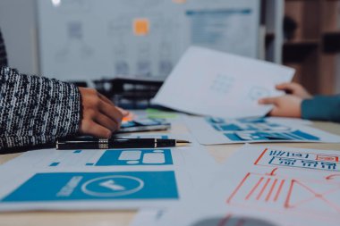 Çalışan bir toplantı sırasında uxui mobil uygulama şablonlarını analiz eden bir grup genç uygulama geliştirici