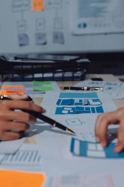 Çalışan bir toplantı sırasında uxui mobil uygulama şablonlarını analiz eden bir grup genç uygulama geliştirici