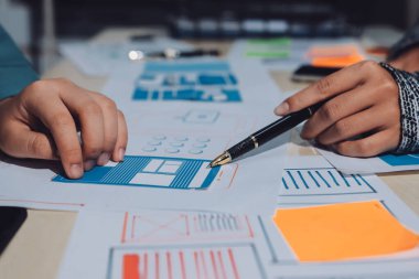 Çalışan bir toplantı sırasında uxui mobil uygulama şablonlarını analiz eden bir grup genç uygulama geliştirici