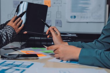 Çalışan bir toplantı sırasında uxui mobil uygulama şablonlarını analiz eden bir grup genç uygulama geliştirici