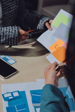 Çalışan bir toplantı sırasında uxui mobil uygulama şablonlarını analiz eden bir grup genç uygulama geliştirici
