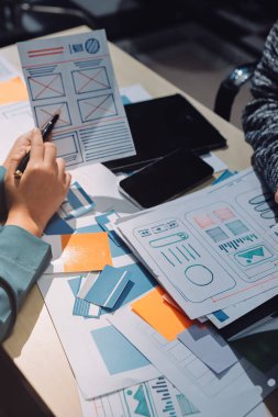 Çalışan bir toplantı sırasında uxui mobil uygulama şablonlarını analiz eden bir grup genç uygulama geliştirici