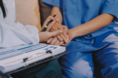 Doktor, klinikteki masada otururken hasta kadına güven veriyor, sadece eller. İlaç ve en iyi hizmet