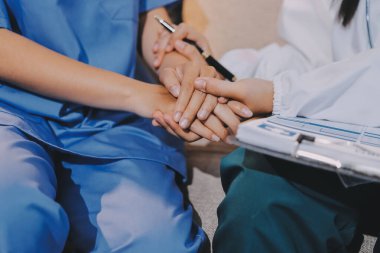 Doktor, klinikteki masada otururken hasta kadına güven veriyor, sadece eller. İlaç ve en iyi hizmet