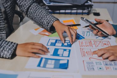 Çalışan bir toplantı sırasında uxui mobil uygulama şablonlarını analiz eden bir grup genç uygulama geliştirici