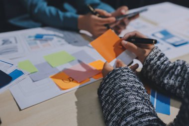 Çalışan bir toplantı sırasında uxui mobil uygulama şablonlarını analiz eden bir grup genç uygulama geliştirici