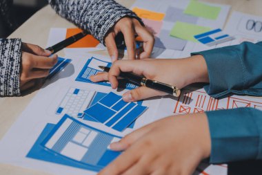 Çalışan bir toplantı sırasında uxui mobil uygulama şablonlarını analiz eden bir grup genç uygulama geliştirici