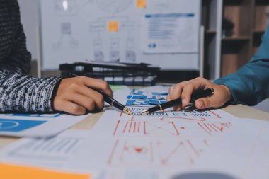 Çalışan bir toplantı sırasında uxui mobil uygulama şablonlarını analiz eden bir grup genç uygulama geliştirici