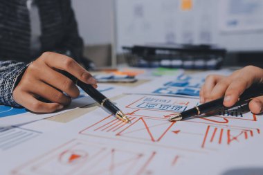 Çalışan bir toplantı sırasında uxui mobil uygulama şablonlarını analiz eden bir grup genç uygulama geliştirici