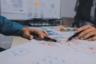 Çalışan bir toplantı sırasında uxui mobil uygulama şablonlarını analiz eden bir grup genç uygulama geliştirici