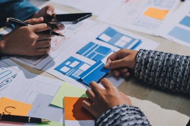 Çalışan bir toplantı sırasında uxui mobil uygulama şablonlarını analiz eden bir grup genç uygulama geliştirici