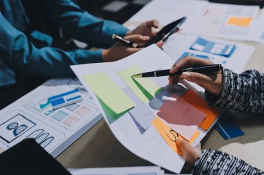 Çalışan bir toplantı sırasında uxui mobil uygulama şablonlarını analiz eden bir grup genç uygulama geliştirici