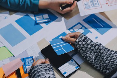 Çalışan bir toplantı sırasında uxui mobil uygulama şablonlarını analiz eden bir grup genç uygulama geliştirici