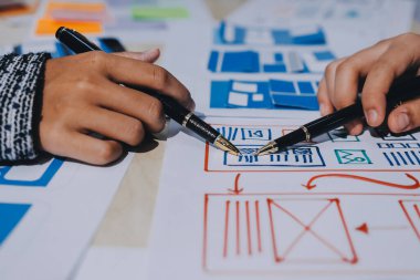 Çalışan bir toplantı sırasında uxui mobil uygulama şablonlarını analiz eden bir grup genç uygulama geliştirici