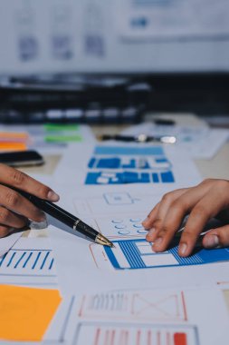 Çalışan bir toplantı sırasında uxui mobil uygulama şablonlarını analiz eden bir grup genç uygulama geliştirici