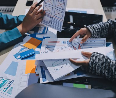 Çalışan bir toplantı sırasında uxui mobil uygulama şablonlarını analiz eden bir grup genç uygulama geliştirici