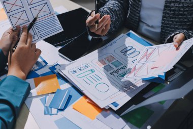 Çalışan bir toplantı sırasında uxui mobil uygulama şablonlarını analiz eden bir grup genç uygulama geliştirici