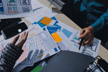 Çalışan bir toplantı sırasında uxui mobil uygulama şablonlarını analiz eden bir grup genç uygulama geliştirici