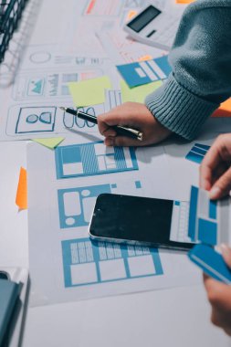 UX UI tasarımcısı prototipi bir telefon üzerinde test ediyor, web sitesi ve mobil uygulama tasarım konseptinde bir web sitesi ve mobil uygulama prototipi için telgraflar üzerinde tartışıyor ve beyin fırtınası yapıyor.
