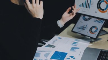 Masadaki finansal verileri ve dizüstü bilgisayarları analiz eden iş adamı.