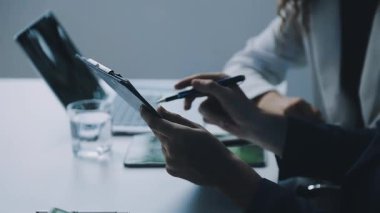 Ofiste otururken iş kadını ellerini tablet bilgisayar kullanarak kapat. Arka planda cep telefonu olan genç bir kadın.