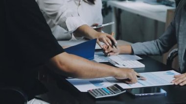 Bir grup genç iş adamı finansal planı tartışıyor ve finansal tabloları modern ofisin masasında analiz ediyorlar.