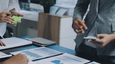 Çalışma ekibi masadaki grafik ve grafikleri tartışıyor ve analiz ediyor.