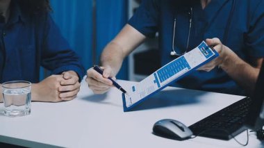 Beyaz gömlekli ve siyah ceketli bir adam dizüstü bilgisayar ve kredi kartı tutuyor..