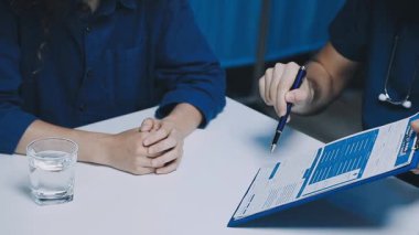 Üniformalı genç bayan doktor elinde kalemle kağıda reçete yazıyor.