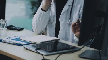 Klinikte kompüter üzerinde çalışan tıp doktoru