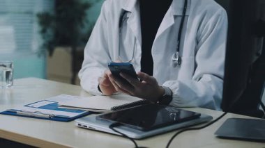 Doktor ofiste akıllı telefon kullanıyor.