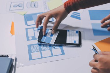 UX UI tasarımcısı prototipi bir telefon üzerinde test ediyor, web sitesi ve mobil uygulama tasarım konseptinde bir web sitesi ve mobil uygulama prototipi için telgraflar üzerinde tartışıyor ve beyin fırtınası yapıyor.