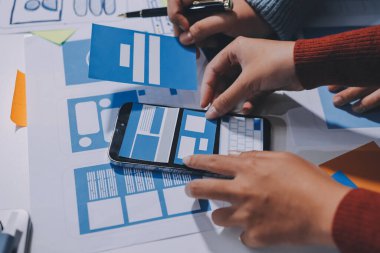 UX UI tasarımcısı prototipi bir telefon üzerinde test ediyor, web sitesi ve mobil uygulama tasarım konseptinde bir web sitesi ve mobil uygulama prototipi için telgraflar üzerinde tartışıyor ve beyin fırtınası yapıyor.