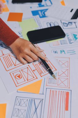 UX UI tasarımcısı prototipi bir telefon üzerinde test ediyor, web sitesi ve mobil uygulama tasarım konseptinde bir web sitesi ve mobil uygulama prototipi için telgraflar üzerinde tartışıyor ve beyin fırtınası yapıyor.