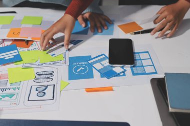 UX UI tasarımcısı prototipi bir telefon üzerinde test ediyor, web sitesi ve mobil uygulama tasarım konseptinde bir web sitesi ve mobil uygulama prototipi için telgraflar üzerinde tartışıyor ve beyin fırtınası yapıyor.