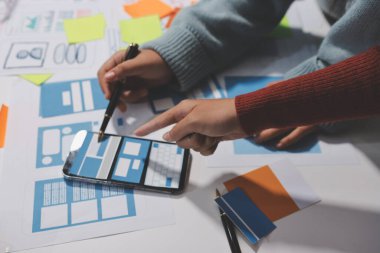 UX UI tasarımcısı prototipi bir telefon üzerinde test ediyor, web sitesi ve mobil uygulama tasarım konseptinde bir web sitesi ve mobil uygulama prototipi için telgraflar üzerinde tartışıyor ve beyin fırtınası yapıyor.