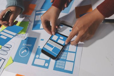 UX UI tasarımcısı prototipi bir telefon üzerinde test ediyor, web sitesi ve mobil uygulama tasarım konseptinde bir web sitesi ve mobil uygulama prototipi için telgraflar üzerinde tartışıyor ve beyin fırtınası yapıyor.