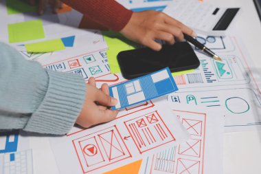 UX UI tasarımcısı prototipi bir telefon üzerinde test ediyor, web sitesi ve mobil uygulama tasarım konseptinde bir web sitesi ve mobil uygulama prototipi için telgraflar üzerinde tartışıyor ve beyin fırtınası yapıyor.