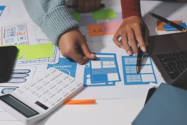 UX UI tasarımcısı prototipi bir telefon üzerinde test ediyor, web sitesi ve mobil uygulama tasarım konseptinde bir web sitesi ve mobil uygulama prototipi için telgraflar üzerinde tartışıyor ve beyin fırtınası yapıyor.