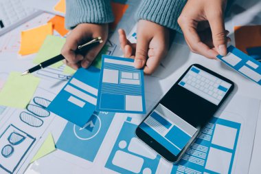 UX UI tasarımcısı prototipi bir telefon üzerinde test ediyor, web sitesi ve mobil uygulama tasarım konseptinde bir web sitesi ve mobil uygulama prototipi için telgraflar üzerinde tartışıyor ve beyin fırtınası yapıyor.