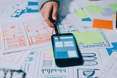 UX UI tasarımcısı prototipi bir telefon üzerinde test ediyor, web sitesi ve mobil uygulama tasarım konseptinde bir web sitesi ve mobil uygulama prototipi için telgraflar üzerinde tartışıyor ve beyin fırtınası yapıyor.